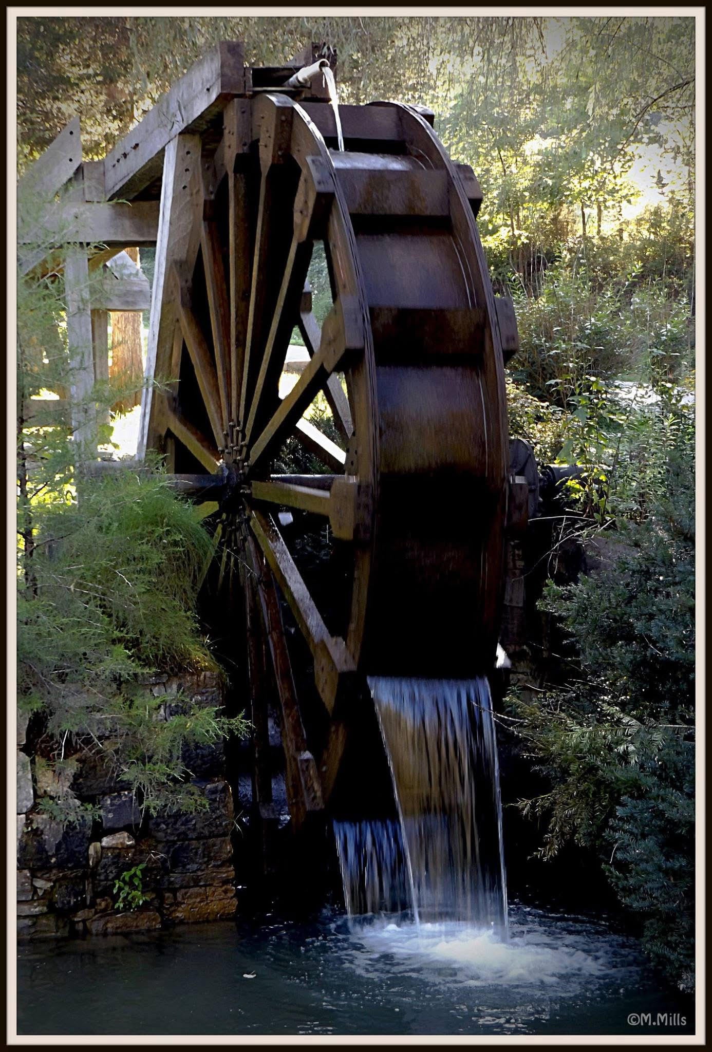 Historic wooden watermill with cascading water surrounded by lush greenery in Pennington Gap, Virginia, photographed by Mary Mills