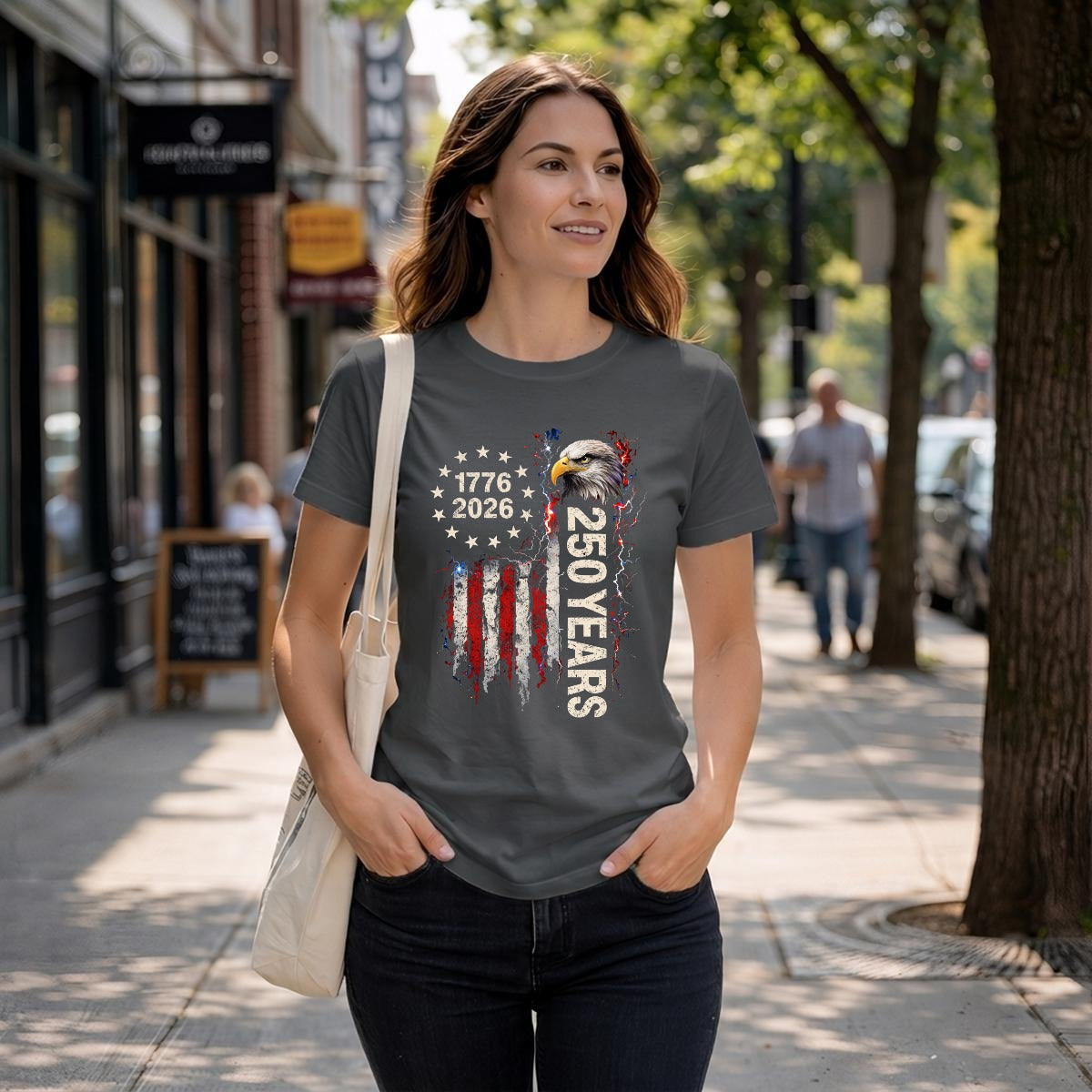 Woman wearing a 1776-2026 patriotic black eagle tee walking on a city street.