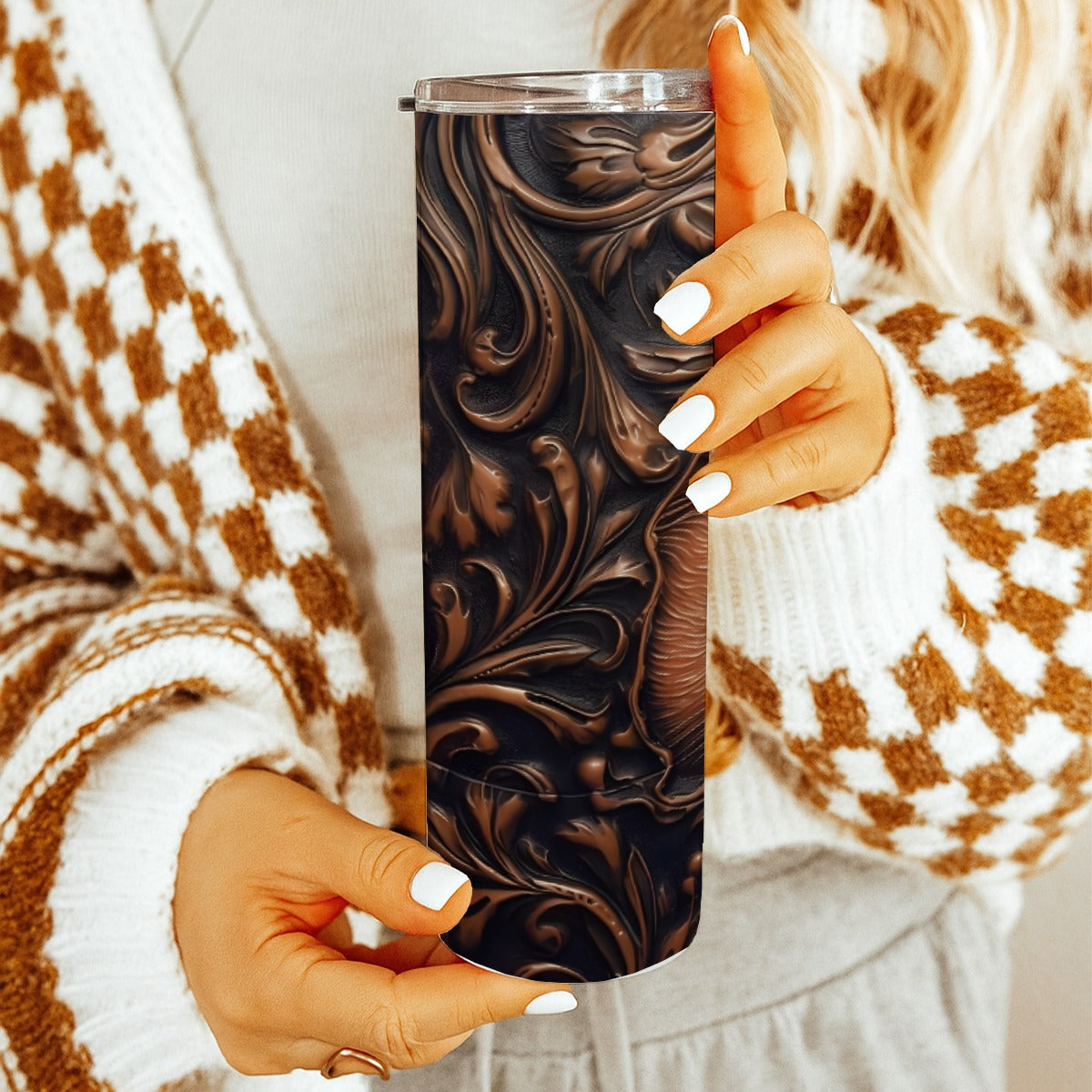 Person holding a20 oz straight tumbler with 3D tooled leather cat design with a cozy indoor background.