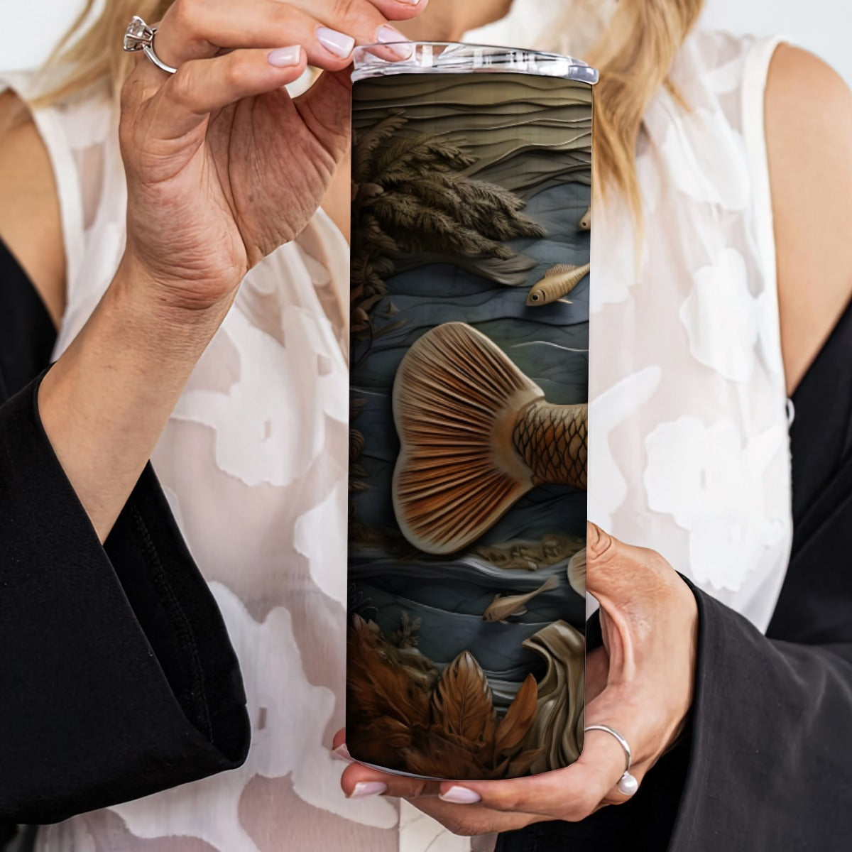 Person holding a 20 oz straight tumbler with 3D tooled leather fish design.