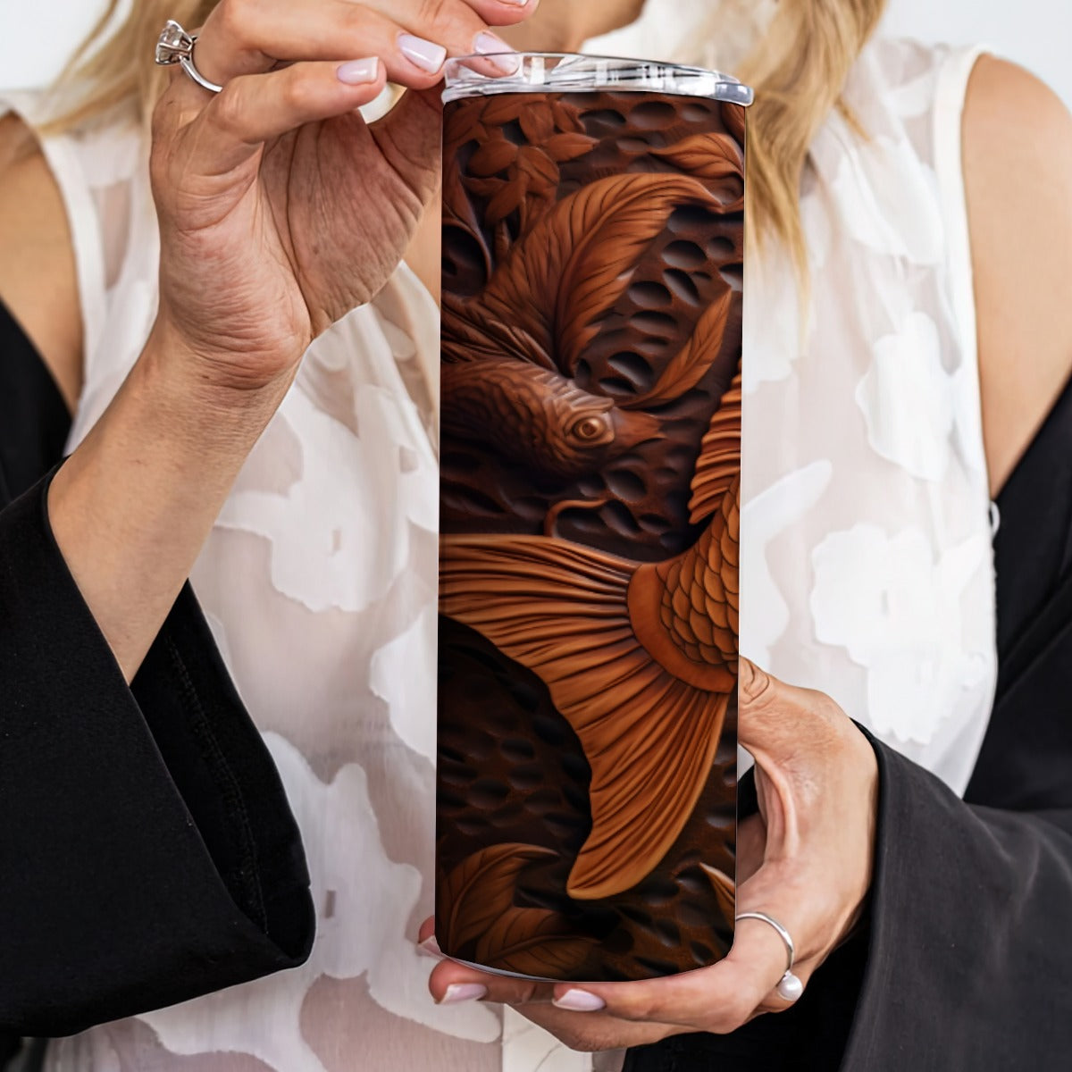 Person holding a 20 oz straight tumbler with 3D tooled leather brown-fish design.