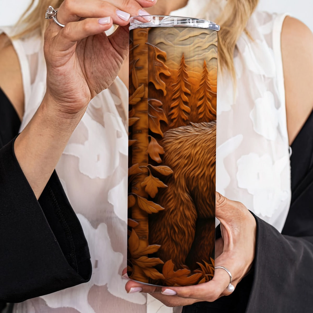 Person holding a 20 oz straight tumbler with 3D tooled leather grizzly bear design.