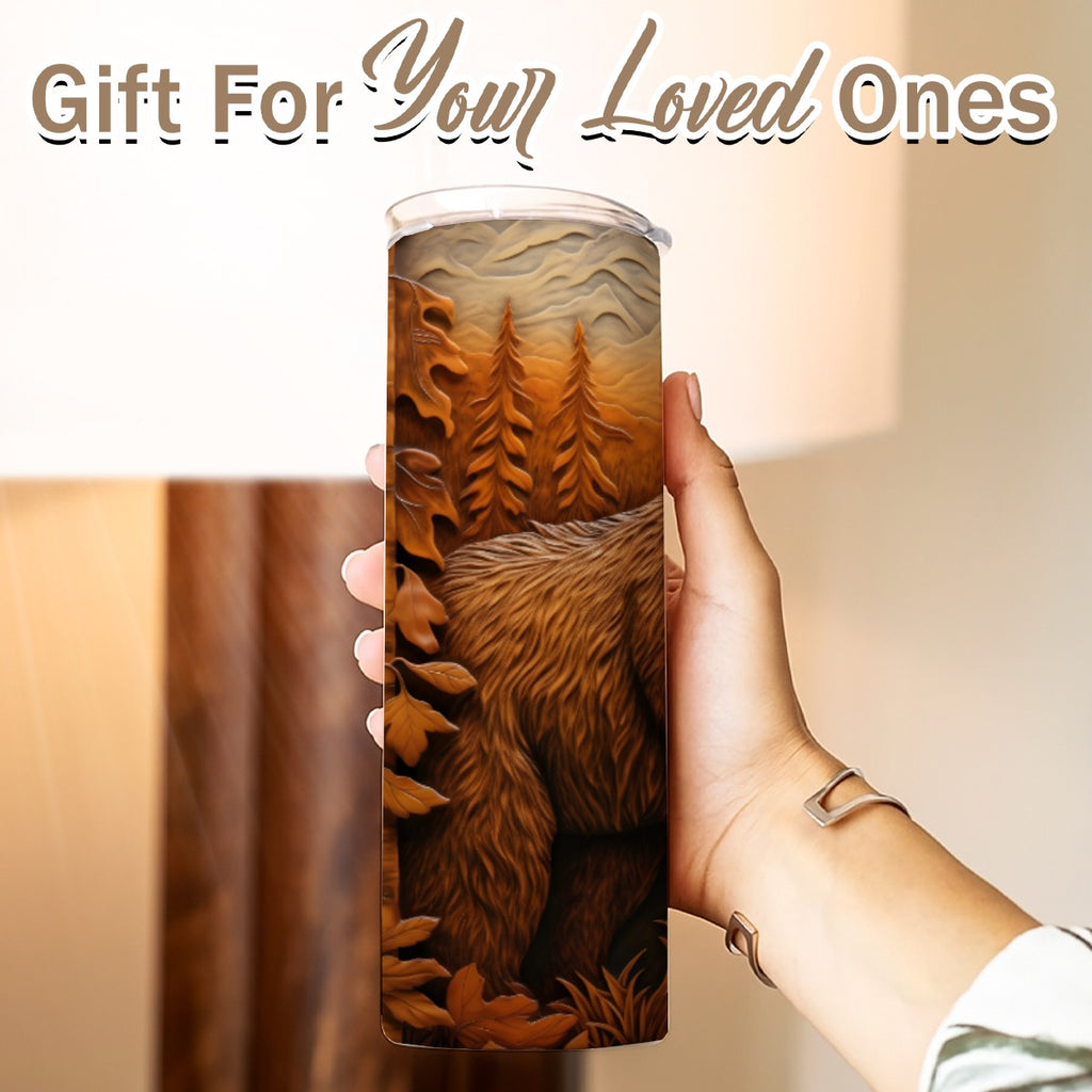 Hand holding a 20 oz straight tumbler with 3D tooled leather grizzly bear design Gift for Your Loved Ones on a blurred background.