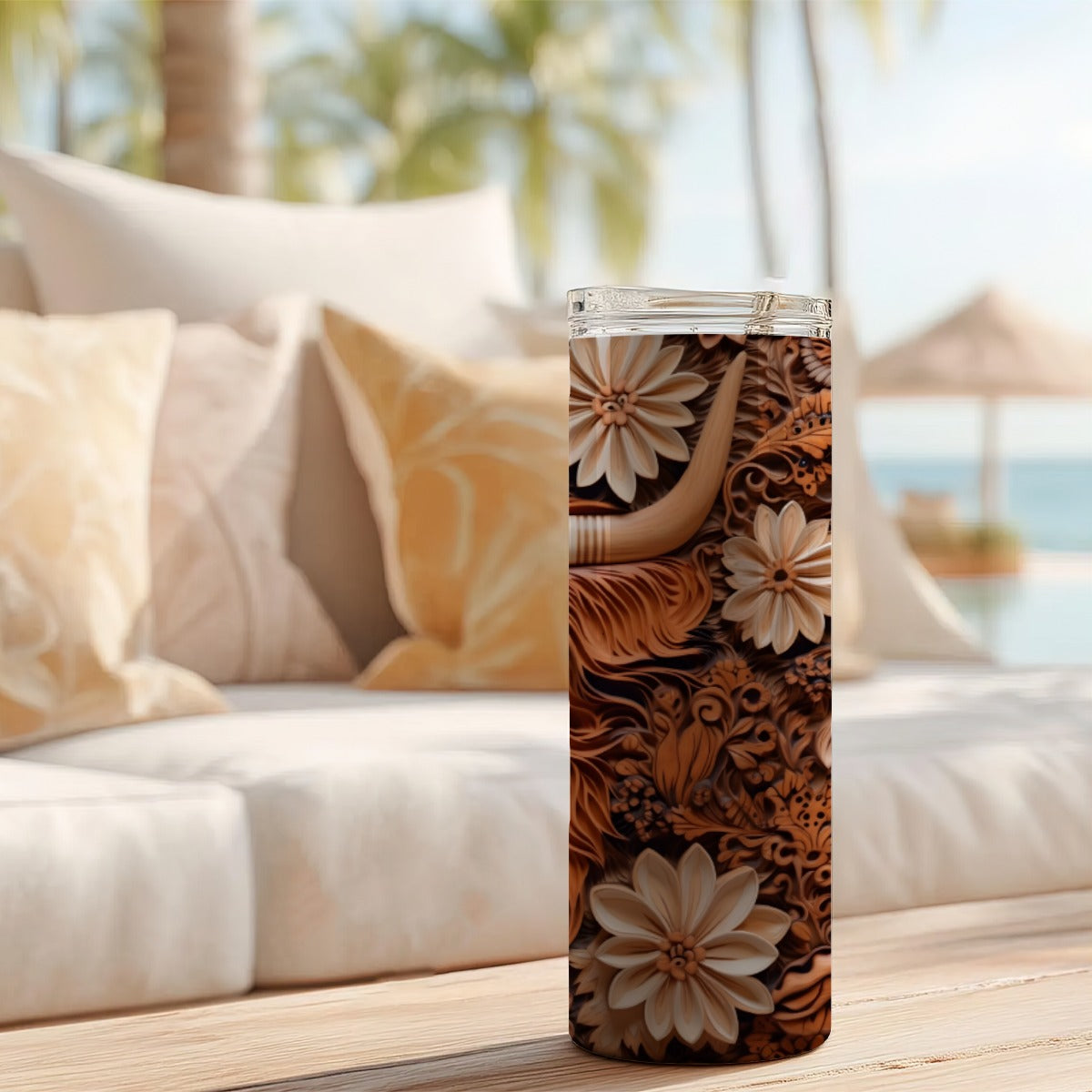 20 oz straight tumbler with 3D tooled leather highlander cow design on a table outdoors.