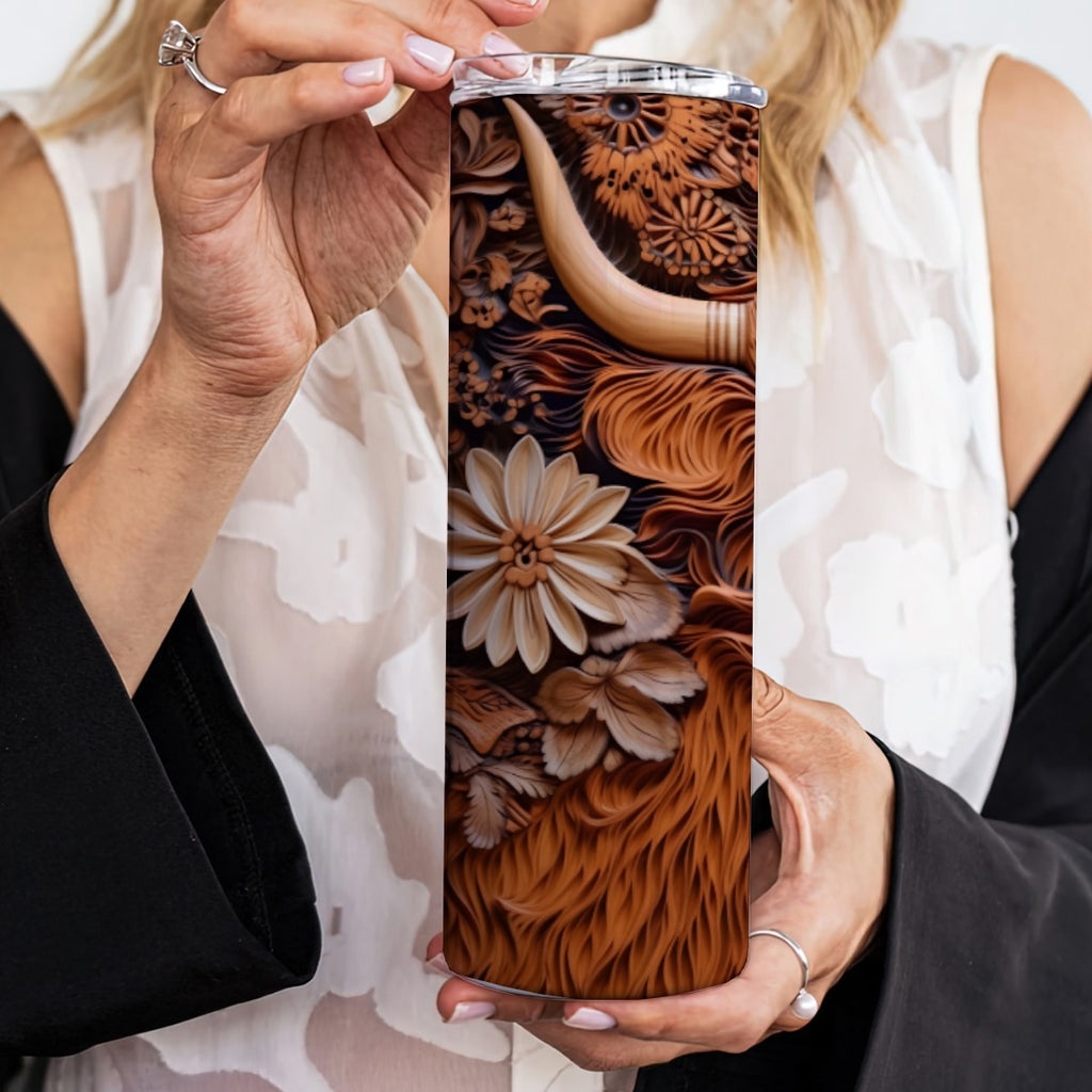 Person holding a 20 oz straight tumbler with 3D tooled leather highlander cow design.