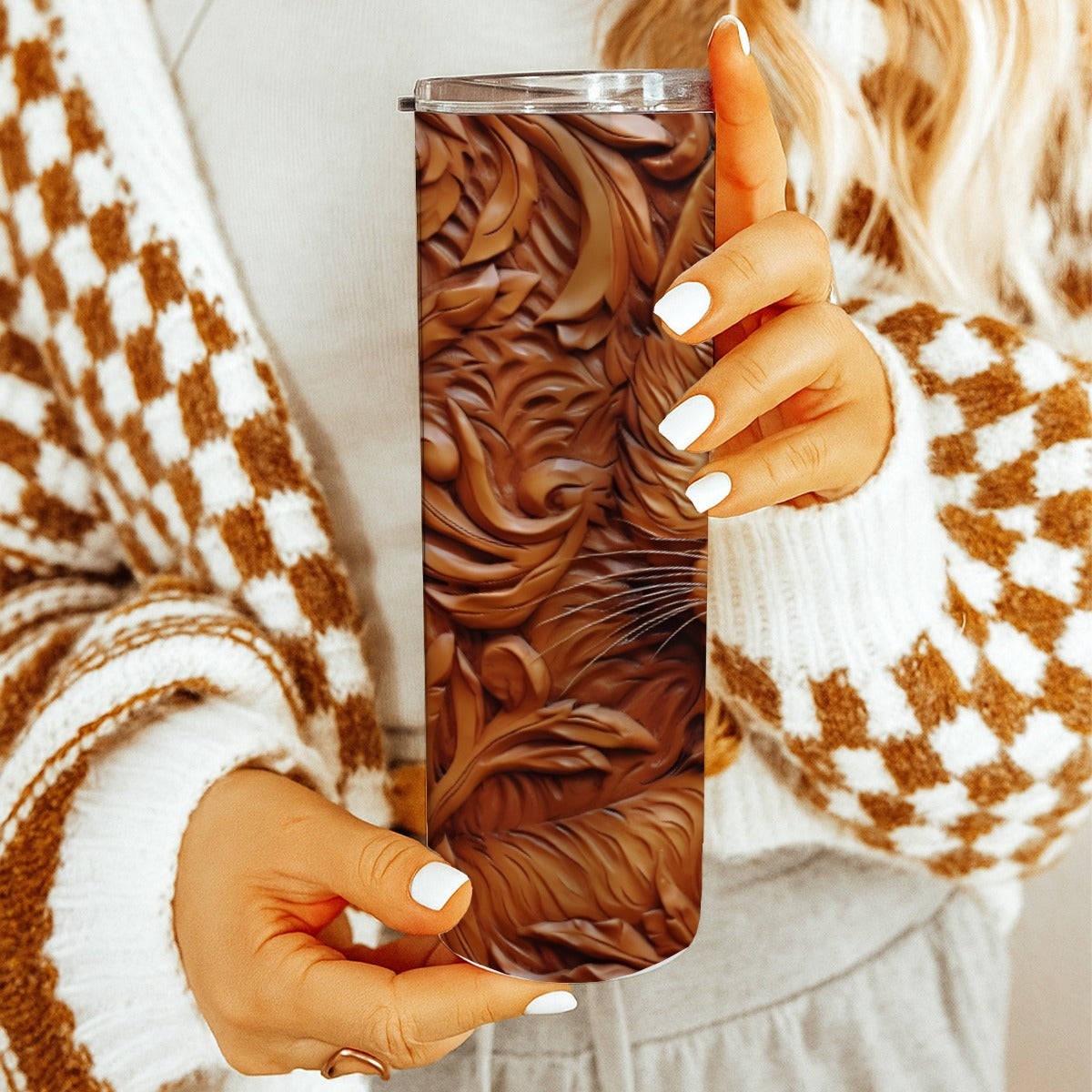 Person holding a20 oz straight tumbler with 3D tooled leather kitten design with a cozy indoor background.