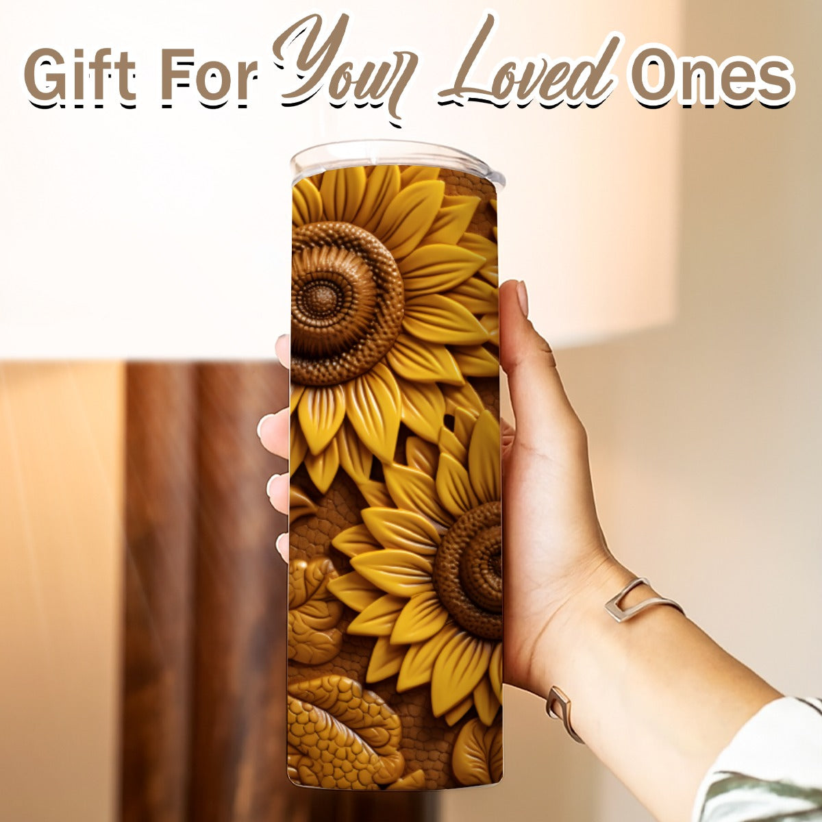 Hand holding a 20 oz straight tumbler- tooled leather sunflower design Gift For Your Loved Ones on a blurred background.
