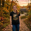 Woman wearing a black t-shirt with graphic design - Black Covered Bridge shirt, in a nature park.