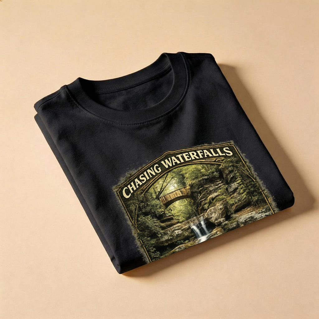 Folded Black t-shirt with graphic design - Chasing Waterfalls Upper Old Man's Cave Shirt on a beige background.