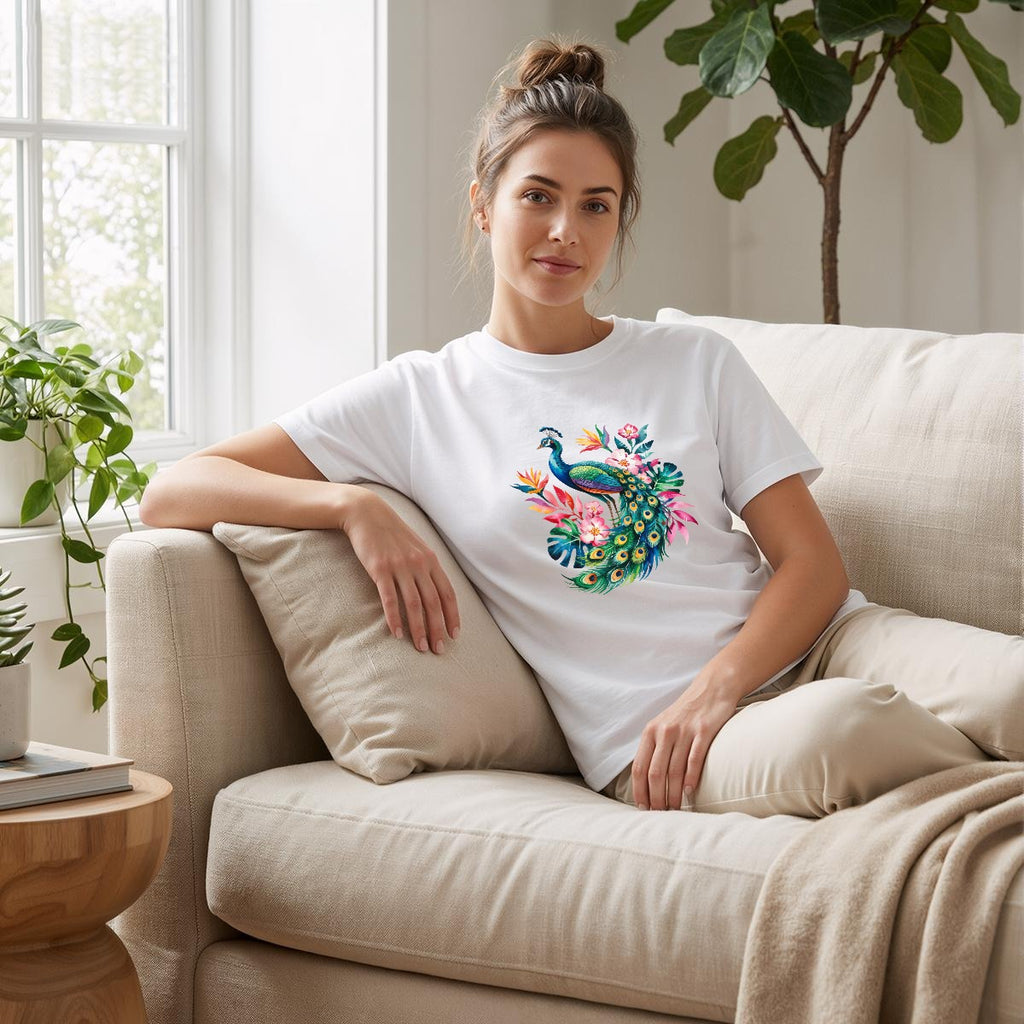 Woman sitting on a couch wearing a white t-shirt with a peacock design.