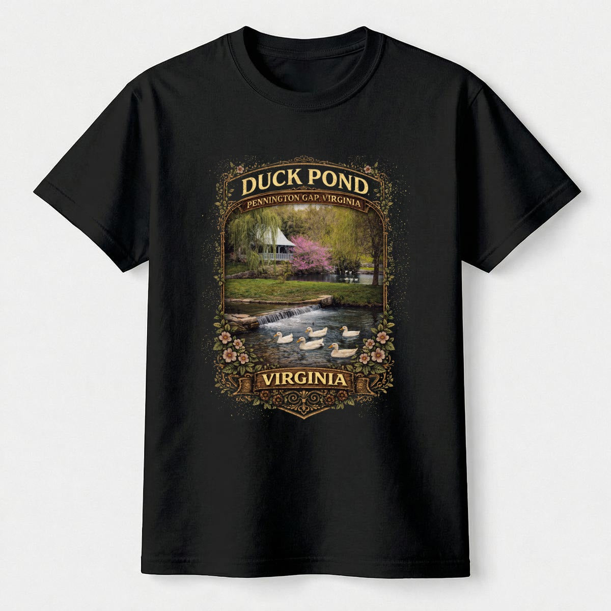 Black t-shirt with a graphic of a duck pond and watermill on a white background.