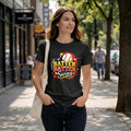 Woman wearing a graphic tee with text -hey-batter-batter-swing on a city sidewalk.