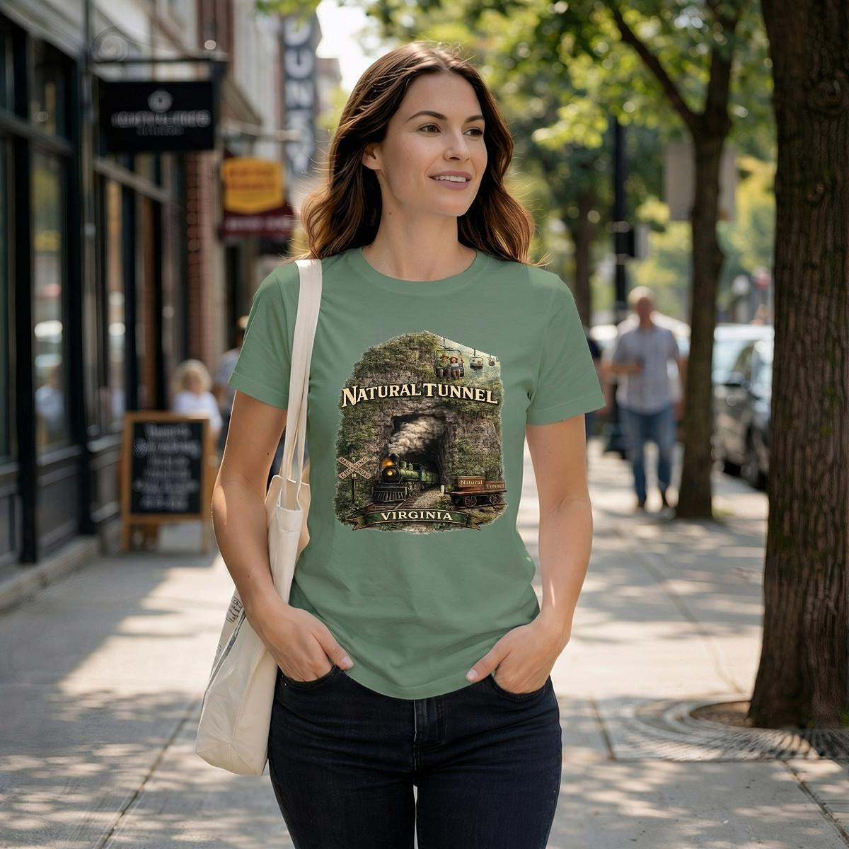 A woman walks down a street wearing a light green graphic t-shirt featuring a steam train coming out of a tunnel.