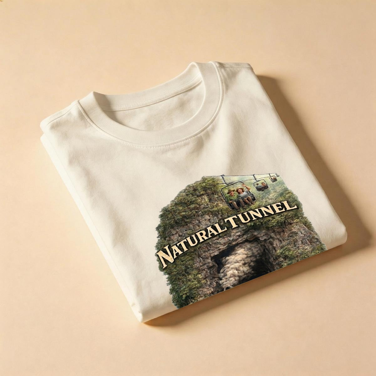 Flat folded cream shirt showing a cave print, chairlift passengers, and Natural Tunnel text