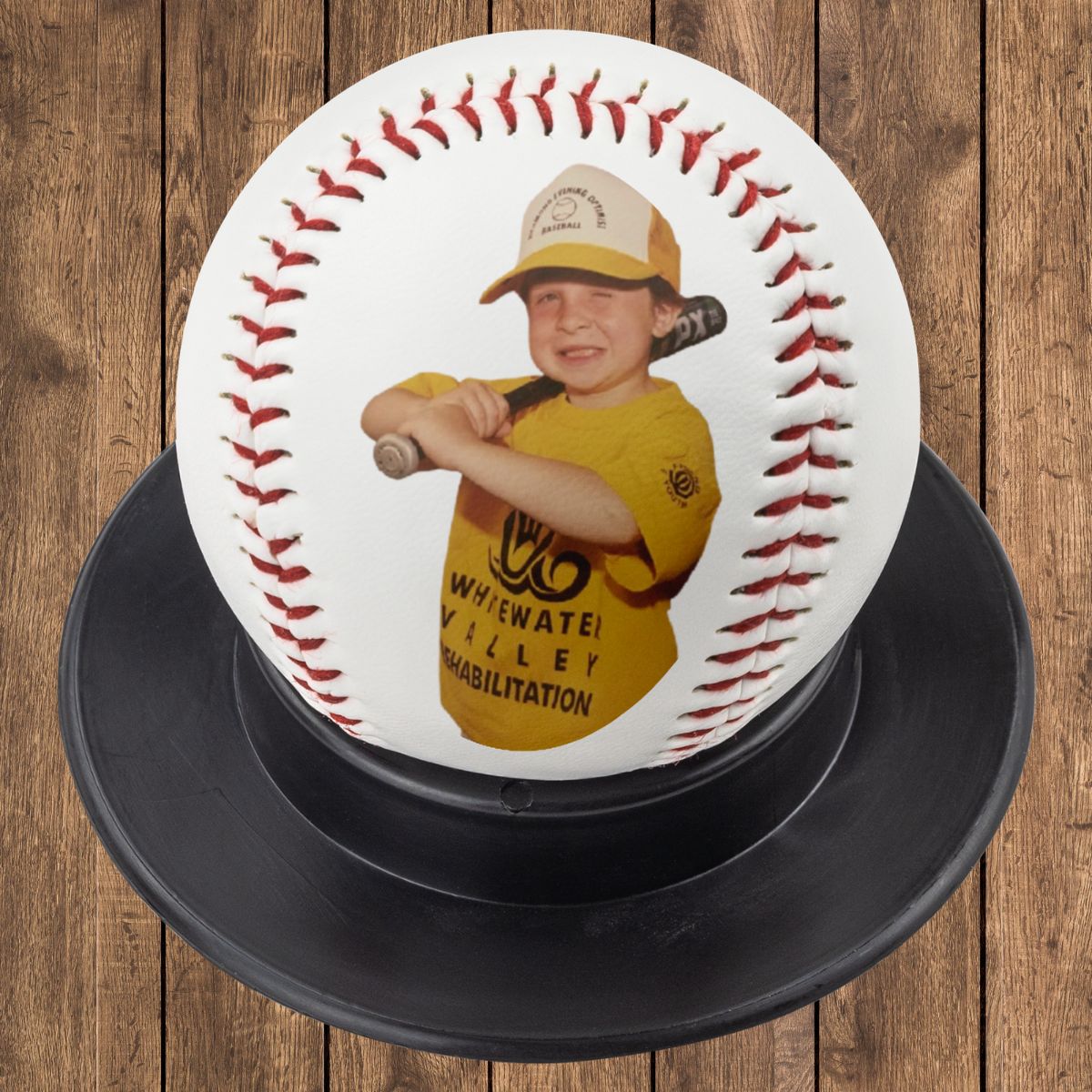 Custom photo baseball on black display stand against rustic wood background.