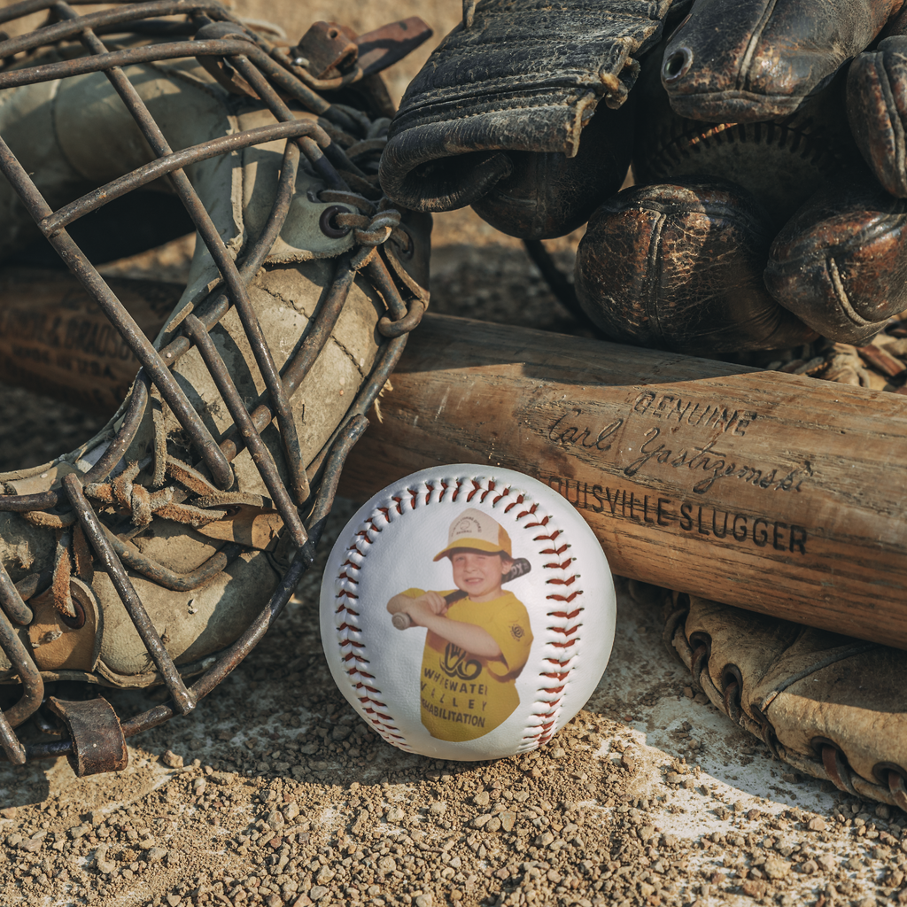 Custom photo baseball on the ground in between rustic wooden bat-guard.