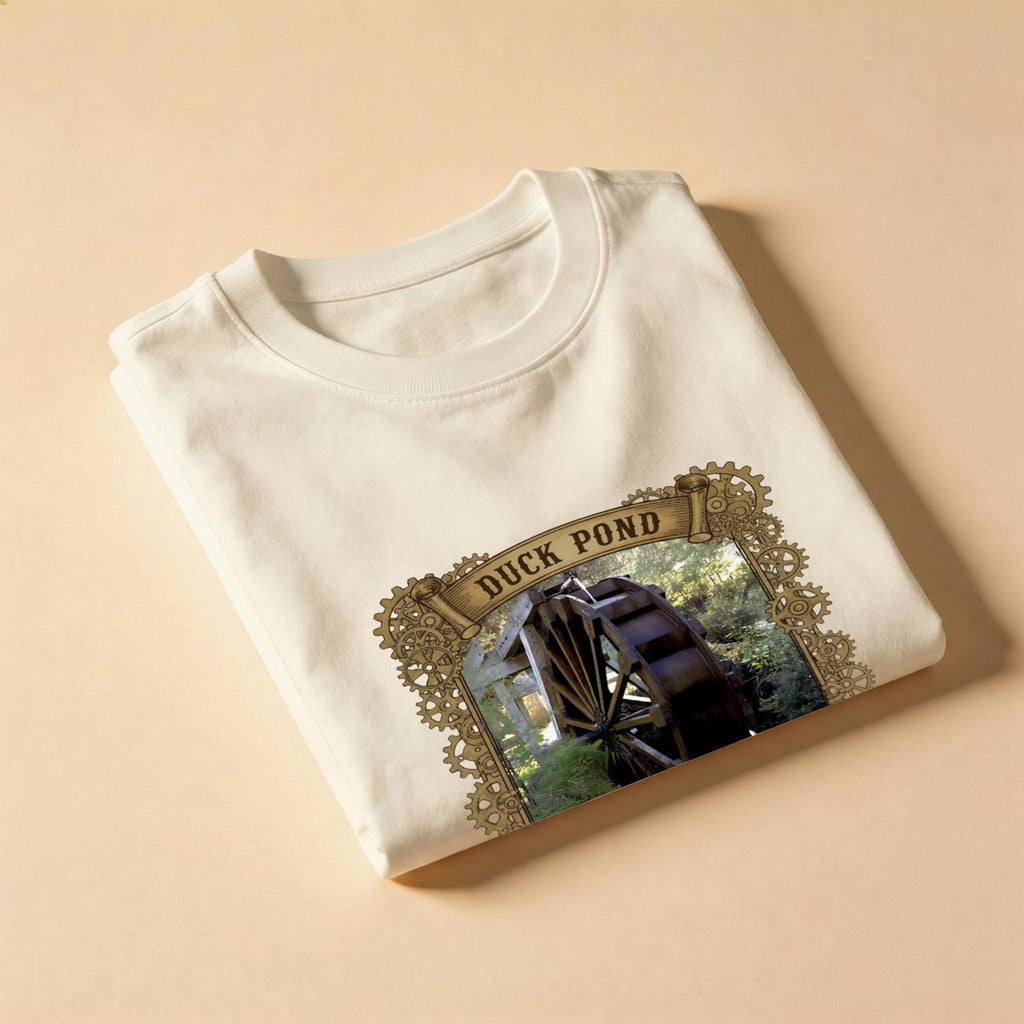 Folded cream-colored t-shirt with Duck Pond graphic design on a beige background.