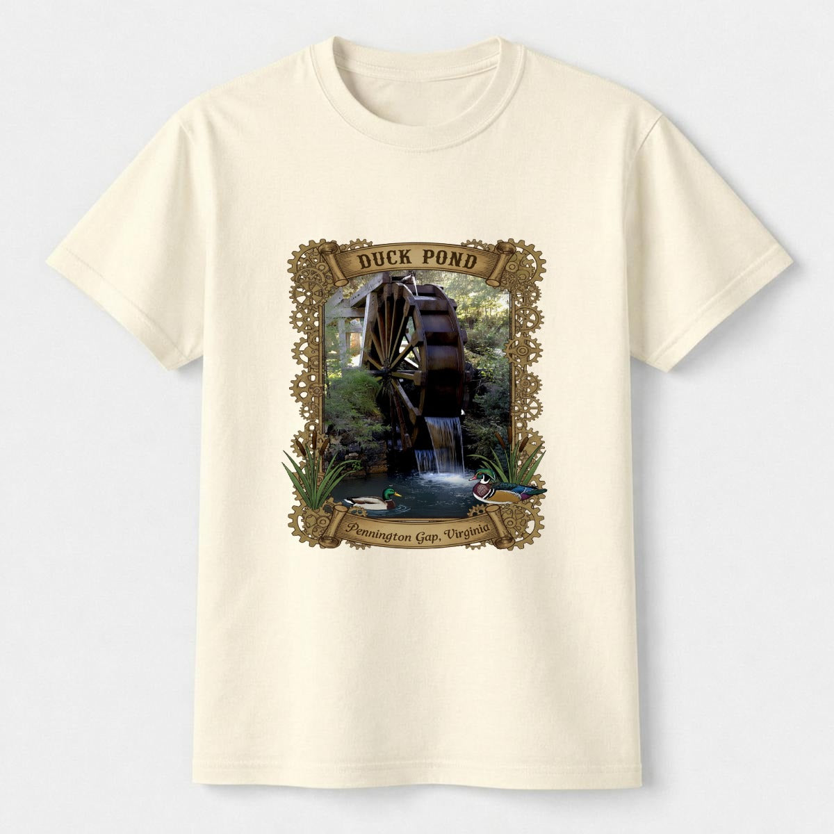 Cream-colored t-shirt with a graphic of a duck pond and watermill on a white background