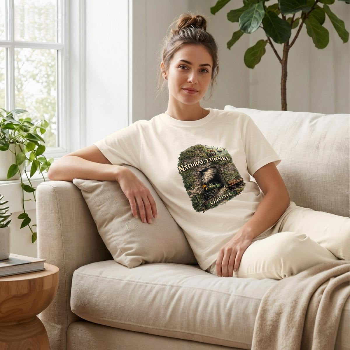 A woman relaxing on a couch wearing a graphic t-shirt featuring a steam train coming out of a cave.